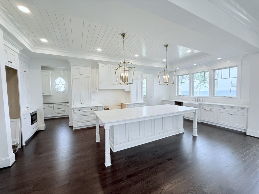 Kitchen with brass cage pendant lights, an oval window, farmhouse sink area, and dark wood floors