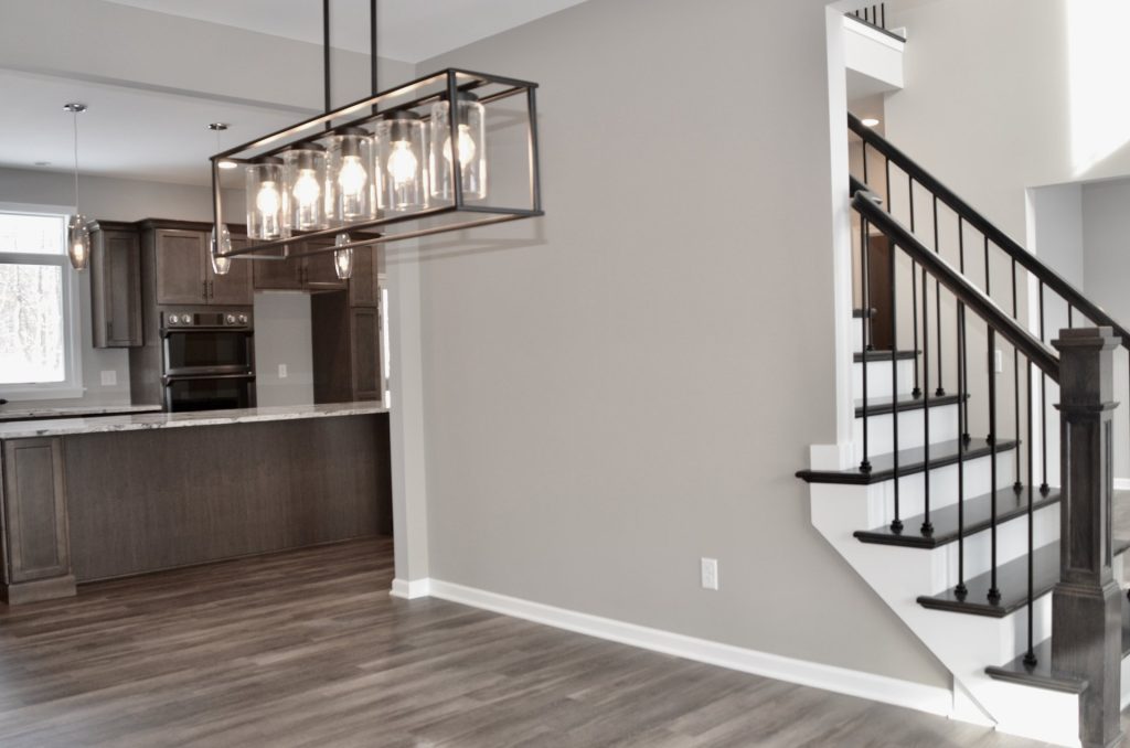 Bradford-Dining-Room-and-Kitchen-View-with-Black-Linear-Chandelier-Dark-Stair-Rail-and-Open-Layout