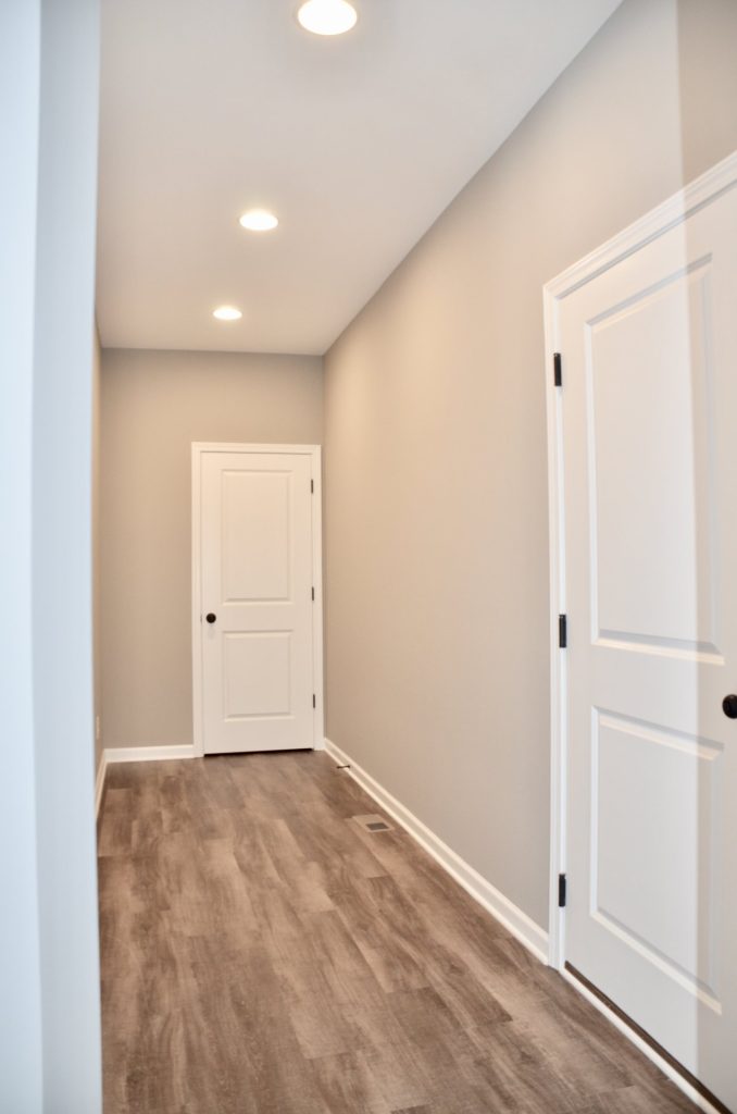 Bradford-Side-Hallway-with-Wood-Look-Flooring-Recessed-Lighting-and-White-Paneled-Doors