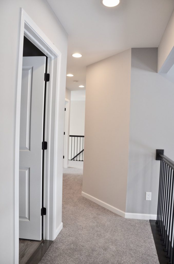 Bradford-Upper-Hallway-with-Gray-Carpet-Black-Railing-and-Multiple-Bedroom-Entries