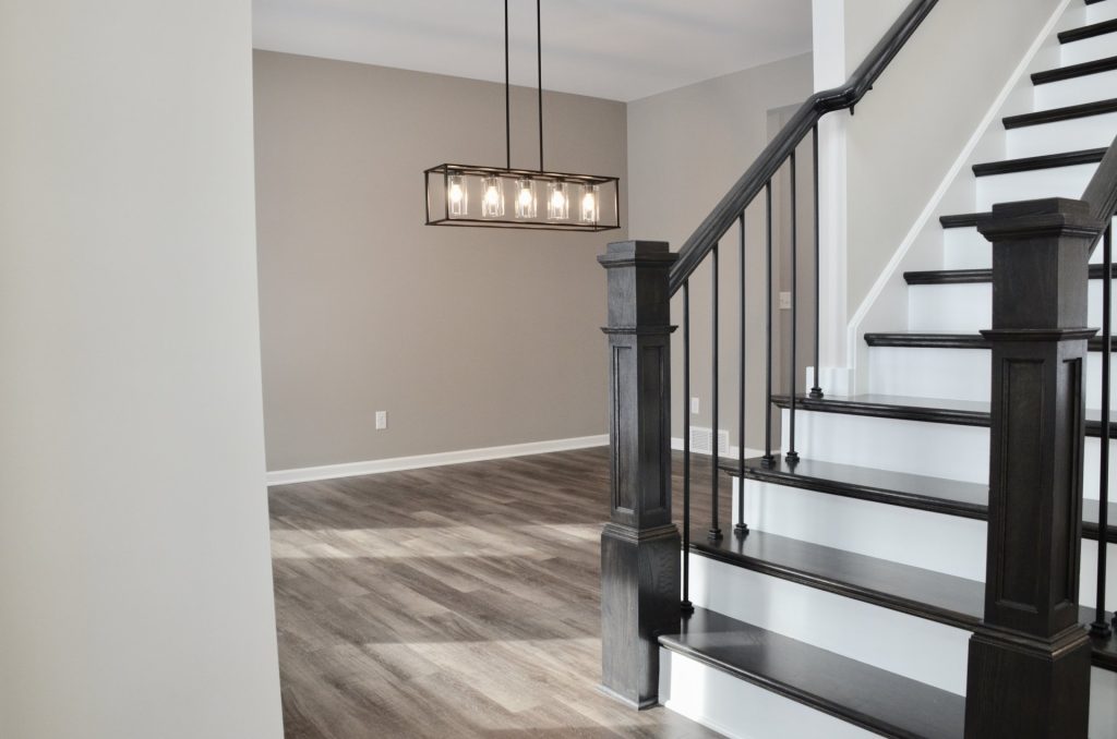 Bradford-Foyer-Staircase-with-Dark-Wood-Railings-White-Risers-and-Open-Two-Story-Wall-Pendant-Lighting