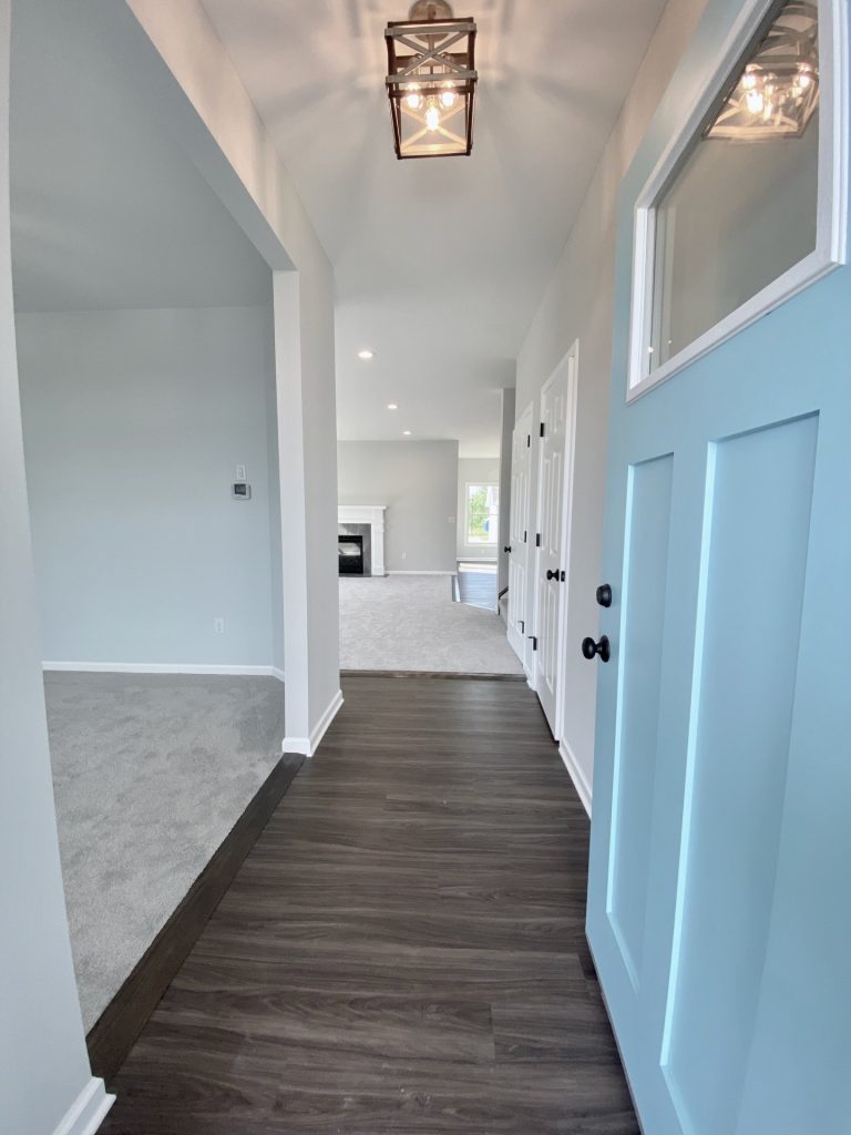The Forsythe Front Entry Hall with Wood-Look Flooring, Blue Front Door, White Trim & Open Layout View