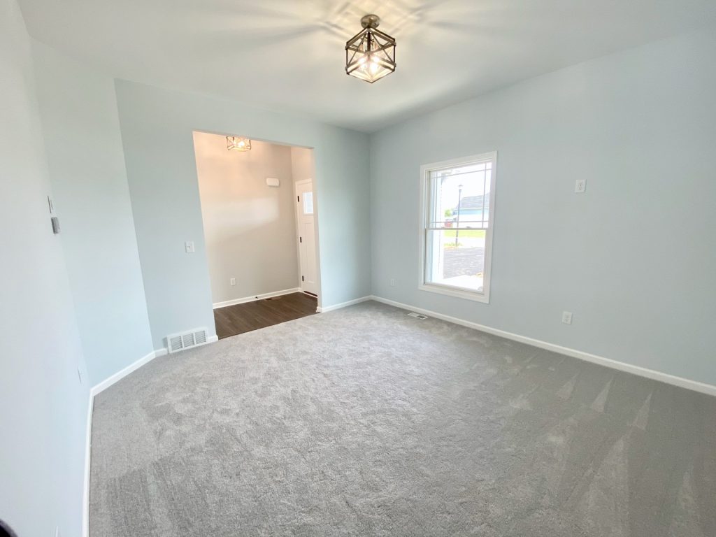 The Forsythe Front Den with Light Carpet, Front Window, White Trim & Entry Hall View