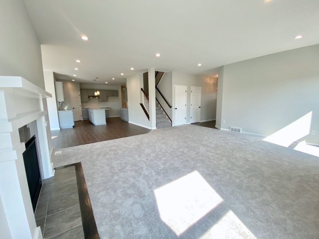 The Forsythe Great Room with Fireplace, Open Kitchen, Wide Carpeted Seating Area & Recessed Lighting