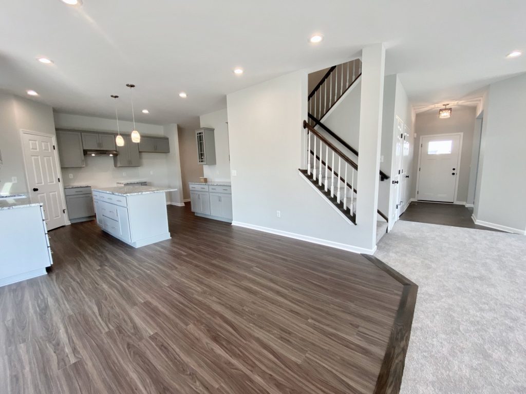 The Forsythe Kitchen with Gray Island, Buffet Cabinets, Wood-Look Flooring & Front Entry View