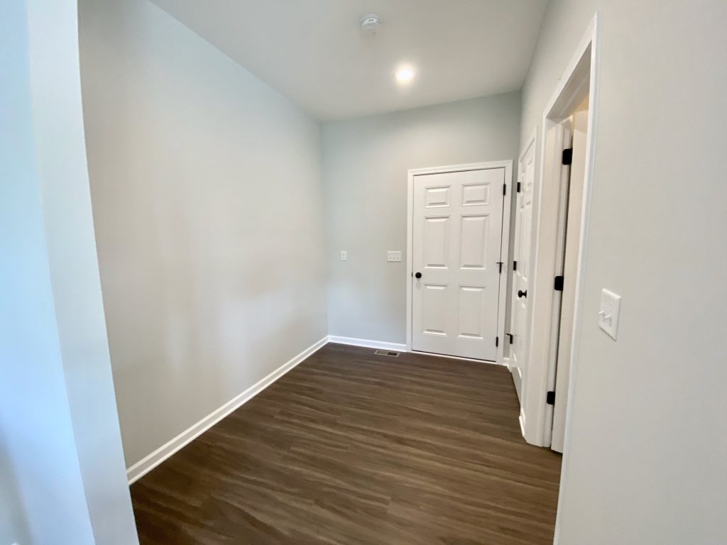The Forsythe Mudroom with Wood-Look Flooring, White Doors, Light Gray Walls & Open Wall Space