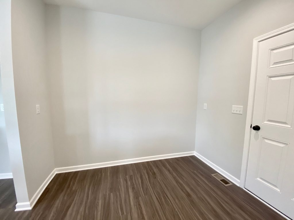 The Forsythe Mudroom Hall with Wood-Look Flooring, White Door, Light Gray Walls & Open Entry View