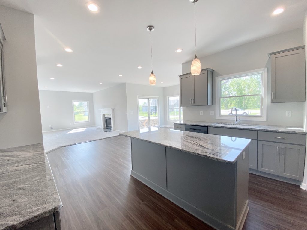 The Forsythe Kitchen with Gray Island, Pendant Lights, Open Great Room, Sliding Glass Door & Large Window