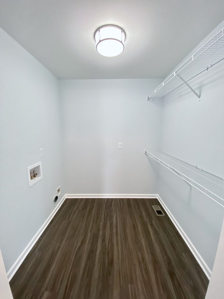 The Forsythe Laundry Room with Wire Shelving, Utility Hookups, Wood-Look Flooring & Light Gray Walls