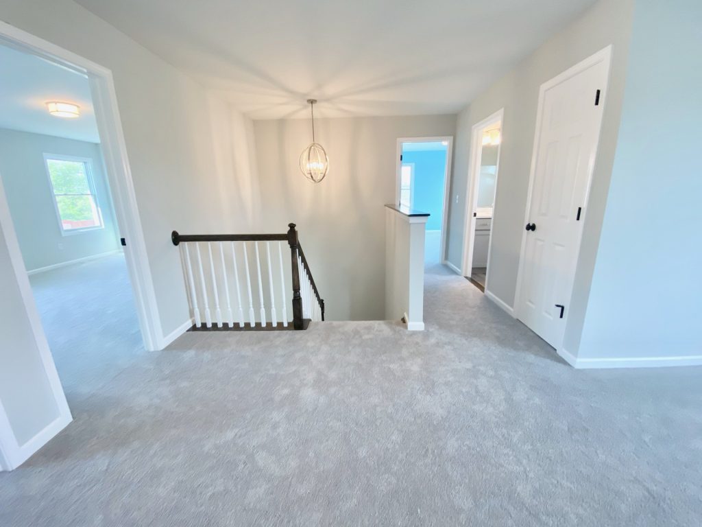 The Forsythe Upper Hallway with Stair Opening, Pendant Light, Light Carpet & Bedroom Entries