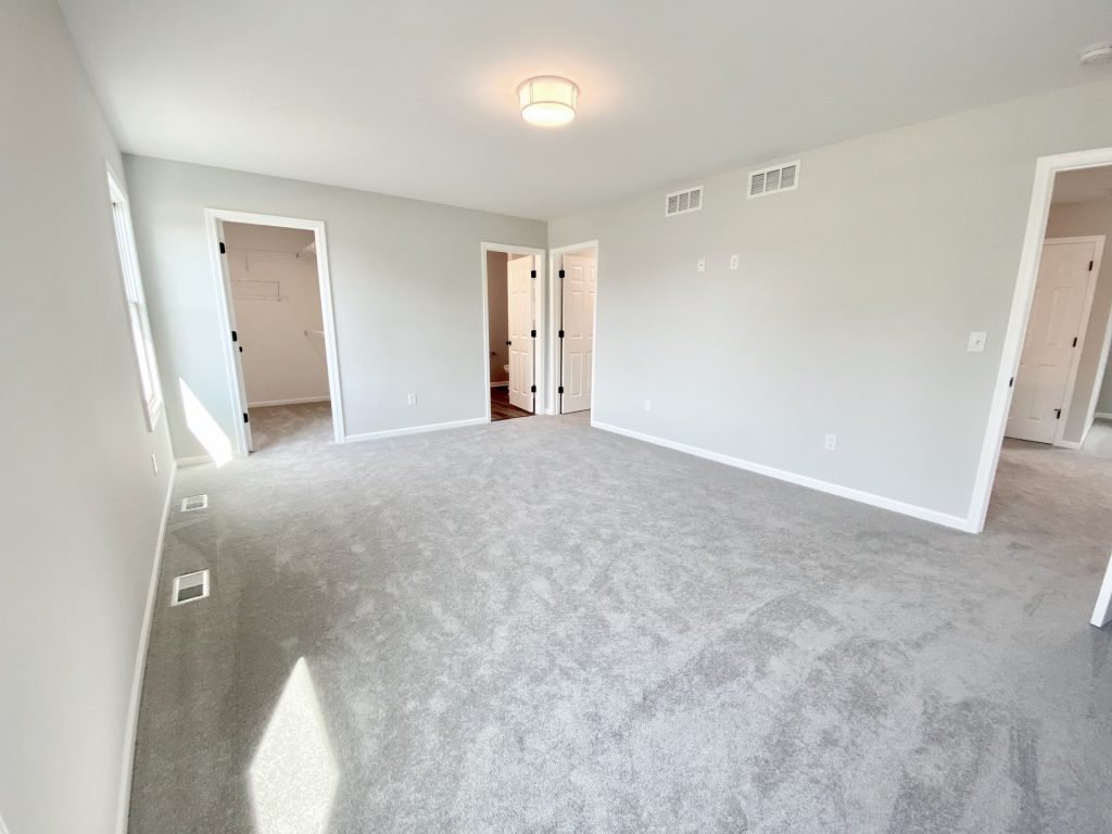 The Forsythe Primary Bedroom with Walk-In Closet, Bath Entry, Light Carpet & Soft Gray Walls