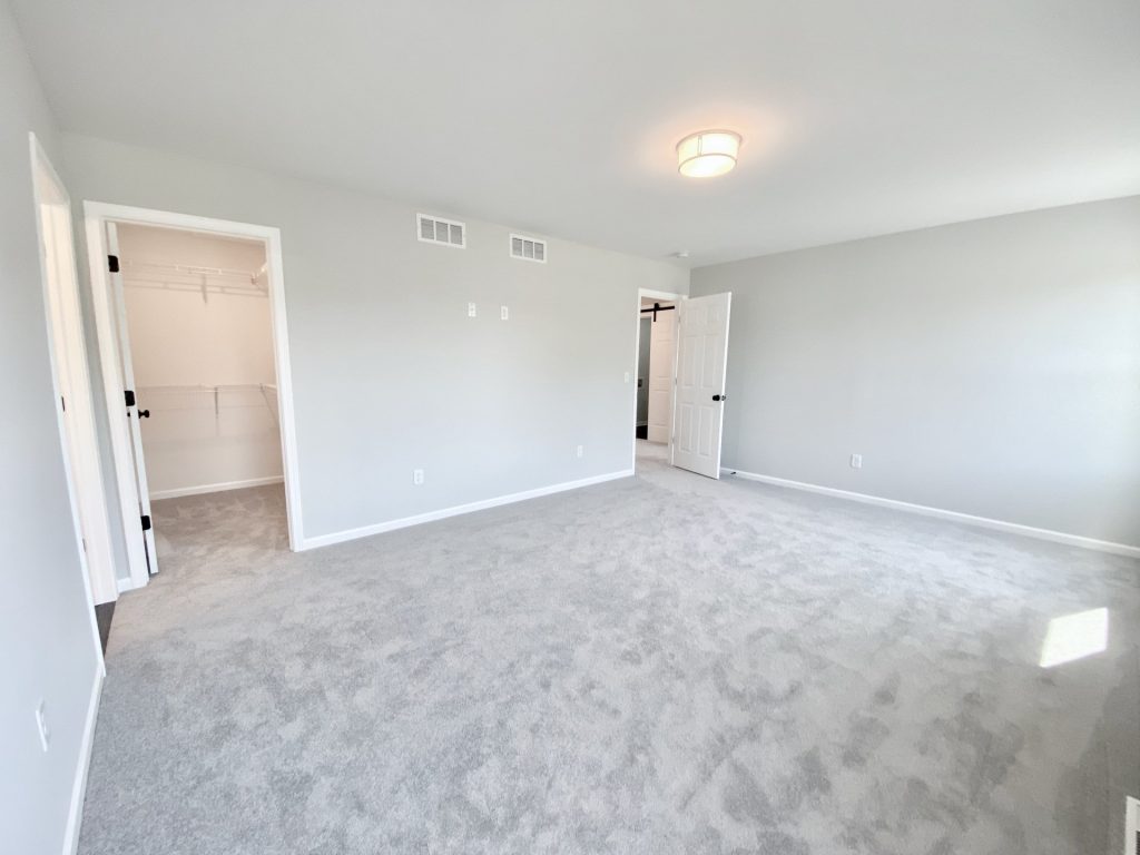 The Forsythe Primary Bedroom with Walk-In Closet, Hall Entry, Light Carpet & Soft Gray Walls