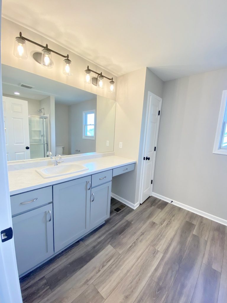 The Forsythe Primary Bathroom with Gray Vanity, Makeup Knee Space, Tile Flooring, Large Mirror & Glass Shower View