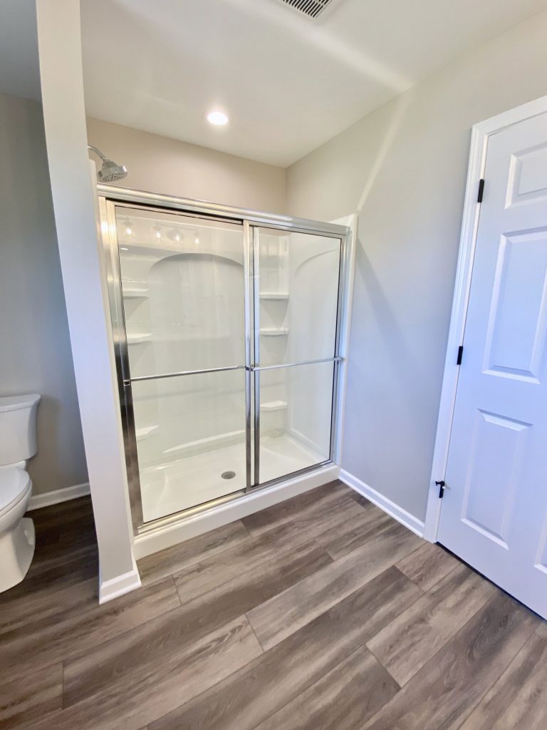 The Forsythe Walk-In Shower with Sliding Glass Doors, Tile Flooring, White Surround & Alternate Angle View