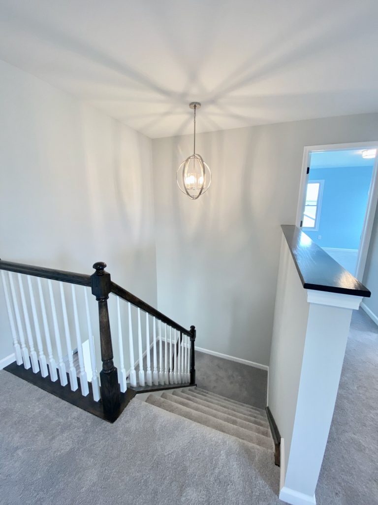 The Forsythe Stair Opening with Pendant Chandelier, Dark Cap Rail, White Balusters & Carpeted Stairs