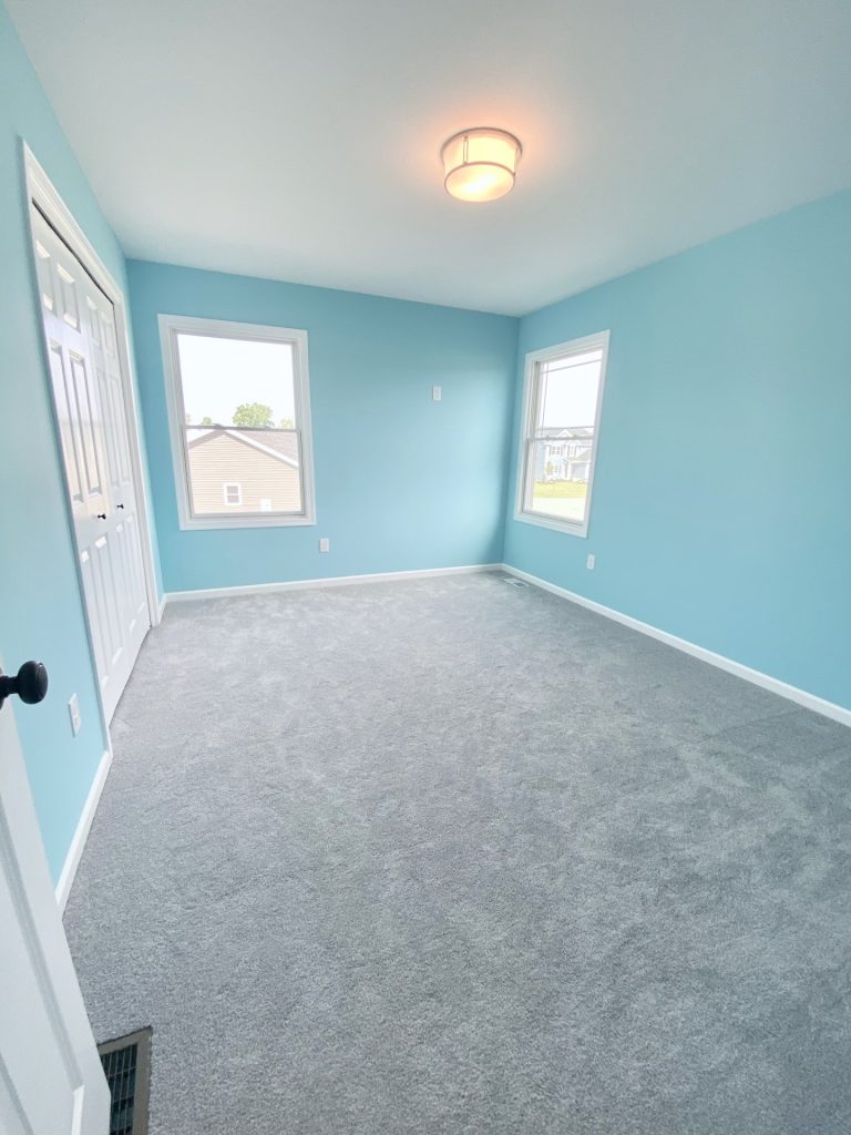 The Forsythe Blue Bedroom with Light Carpet, Two Windows, White Closet Doors & Flush-Mount Ceiling Light