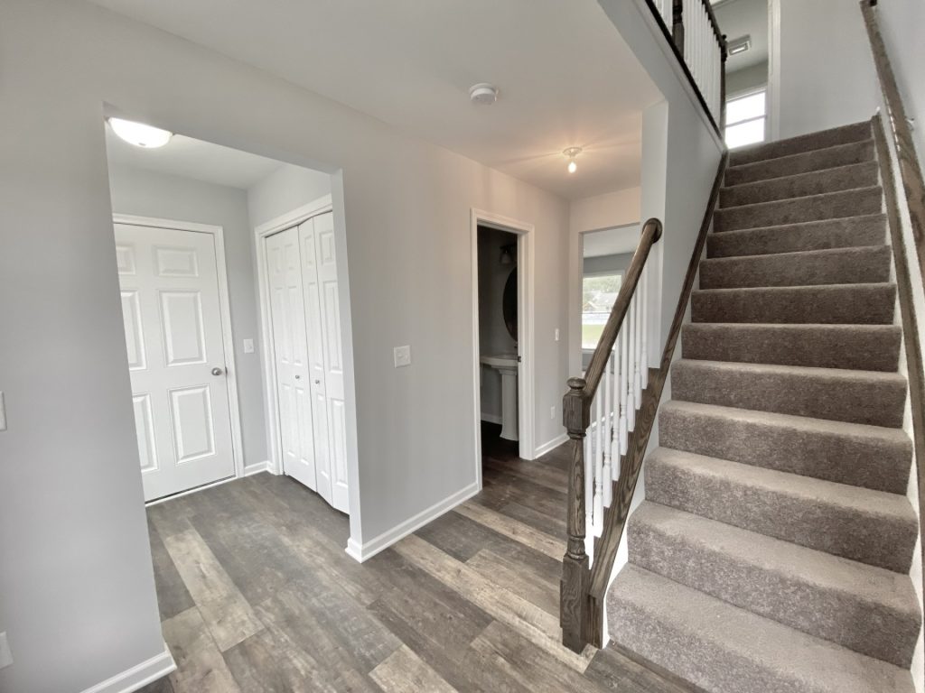 The Mackenzie Front Entry Hall with Carpeted Staircase, Wood-Look Flooring, Gray Walls & White Trim