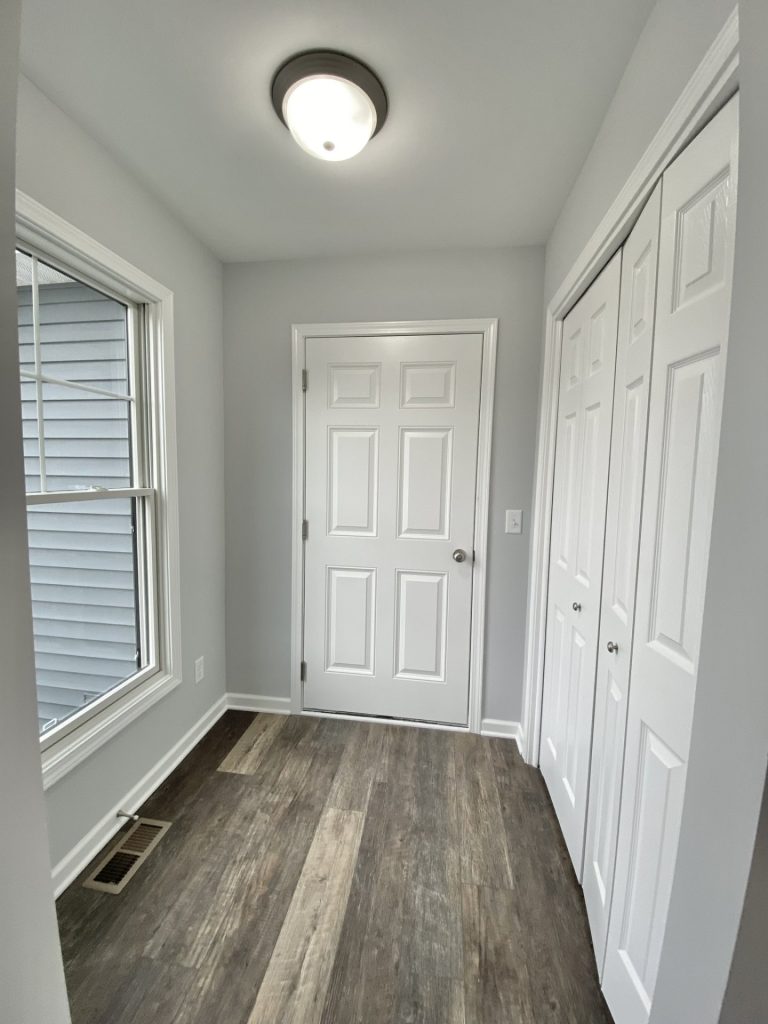 The Mackenzie Mudroom with White Doors, Wood-Look Flooring, Tall Window & Gray Walls