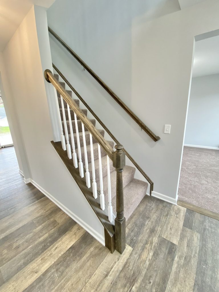 The Mackenzie Staircase with Carpeted Steps, Dark Handrail, White Balusters & Wood-Look Flooring