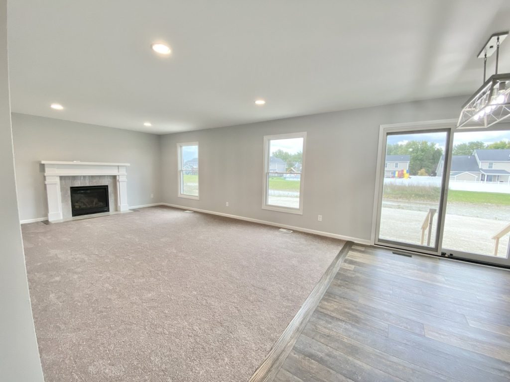 The Mackenzie Great Room with Fireplace, Sliding Glass Door, Neutral Carpet & Open Dinette