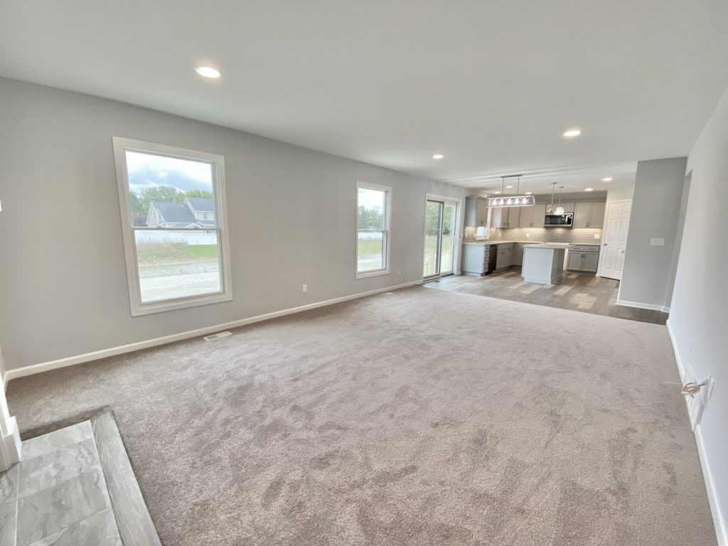 The Mackenzie Great Room with Open Kitchen View, Neutral Carpet, Tall Windows & Recessed Lighting