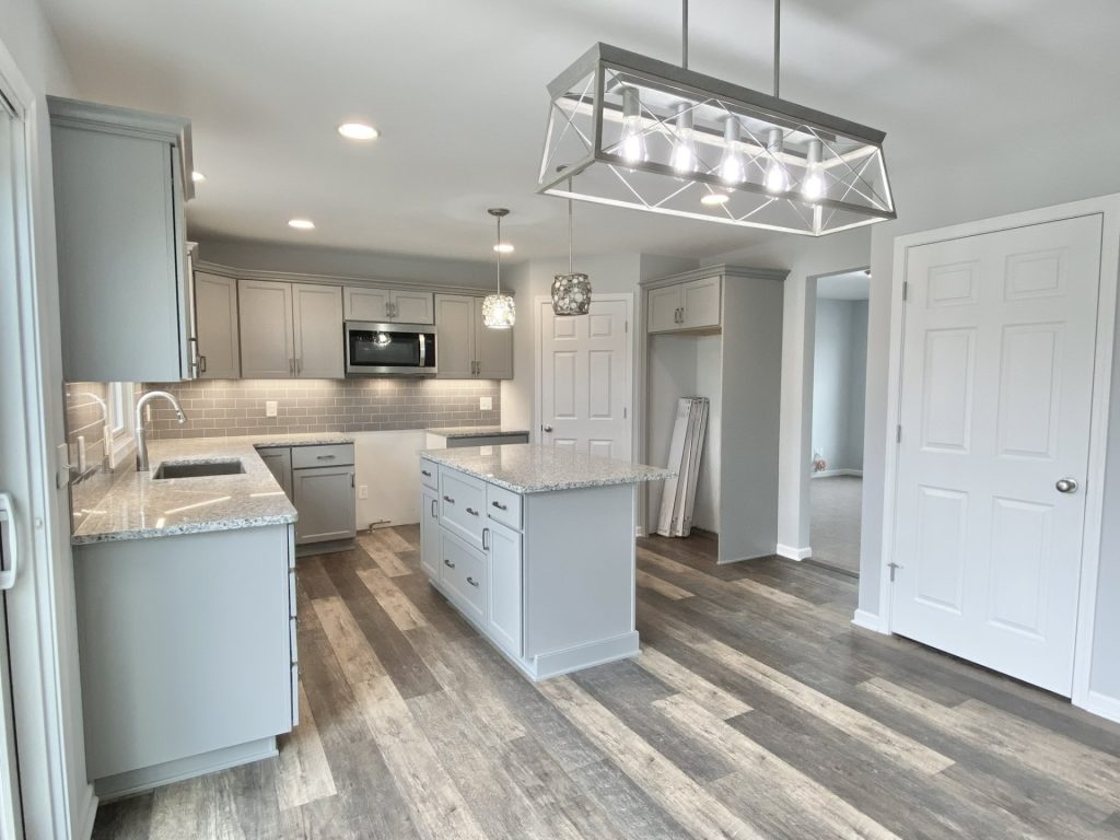 The Mackenzie Kitchen with Gray Cabinetry, Granite Island, Pendant Lights & Tile Backsplash