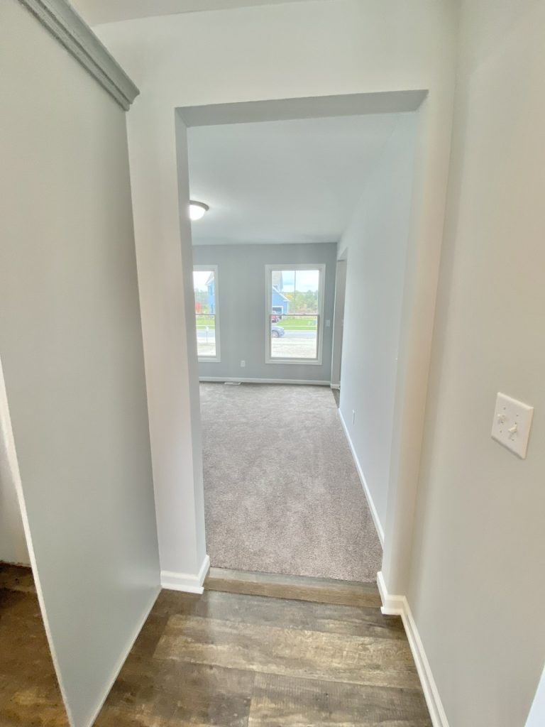 The Mackenzie Hallway to Den with Wood-Look Flooring, Gray Walls, Tall Windows & White Trim