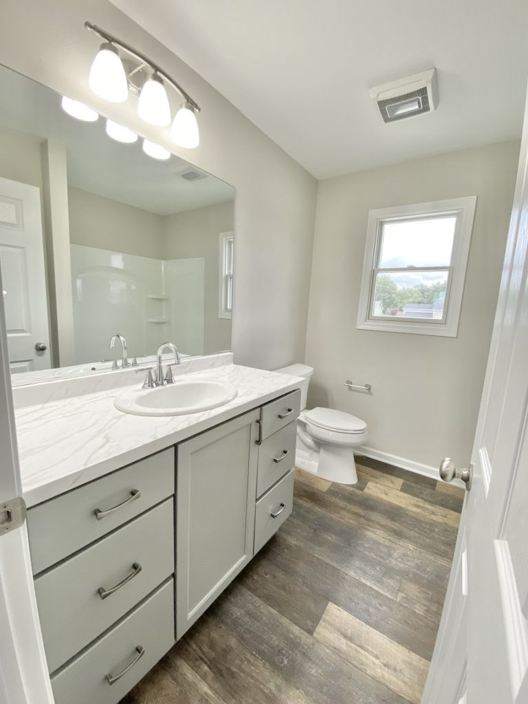 The Mackenzie Full Bathroom with Gray Vanity, Tub-Shower Combo, Wood-Look Flooring & Window Light