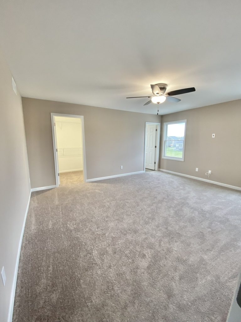 The Mackenzie Primary Bedroom with Neutral Carpet, Ceiling Fan, Walk-In Closet Entry & Single Window