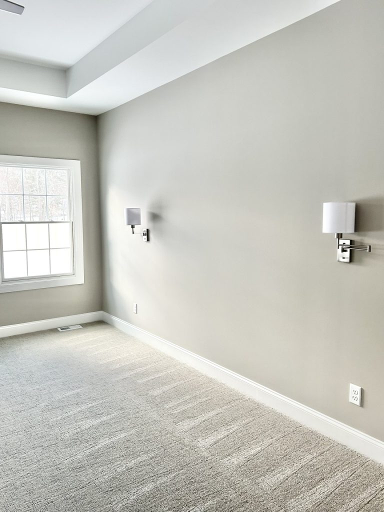 The Maple with Loft Primary Bedroom with Neutral Carpet, Wall Sconces, Tray Ceiling & Window Light