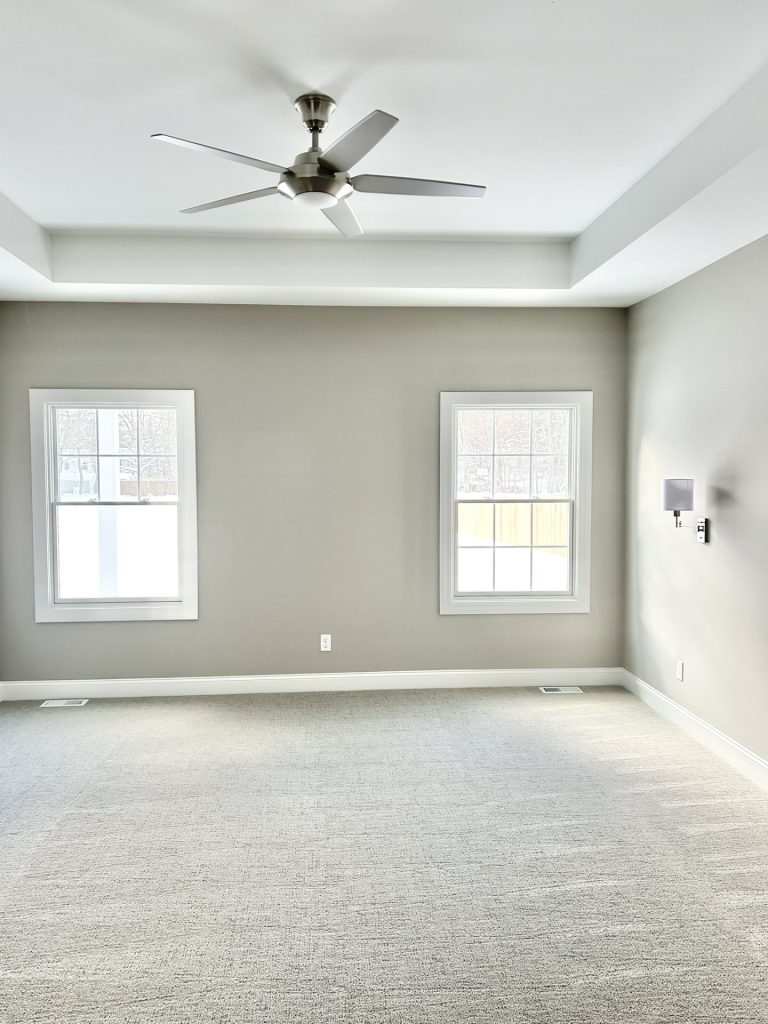 The Maple with Loft Primary Bedroom with Neutral Carpet, Tray Ceiling, Two Windows & Ceiling Fan