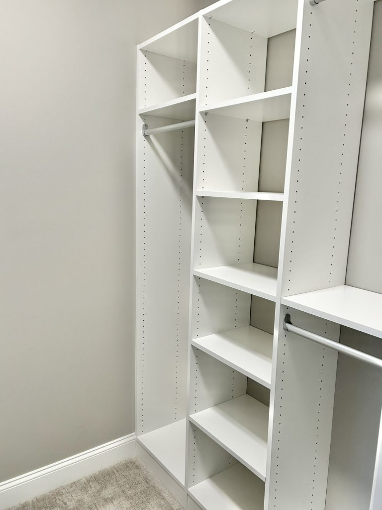 The Maple with Loft Walk-In Closet with Built-In Shelving, Hanging Rods, Neutral Carpet & White Storage System
