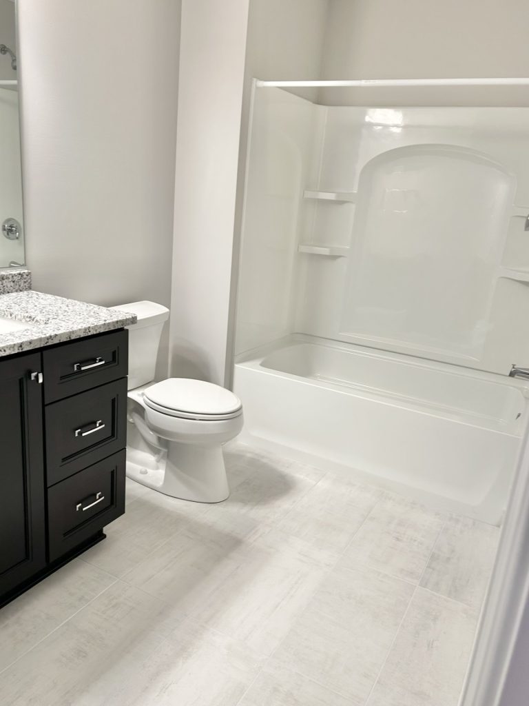 The Maple with Loft Full Bathroom with White Shower-Tub Combo, White Toilet, and Dark Cabinetry