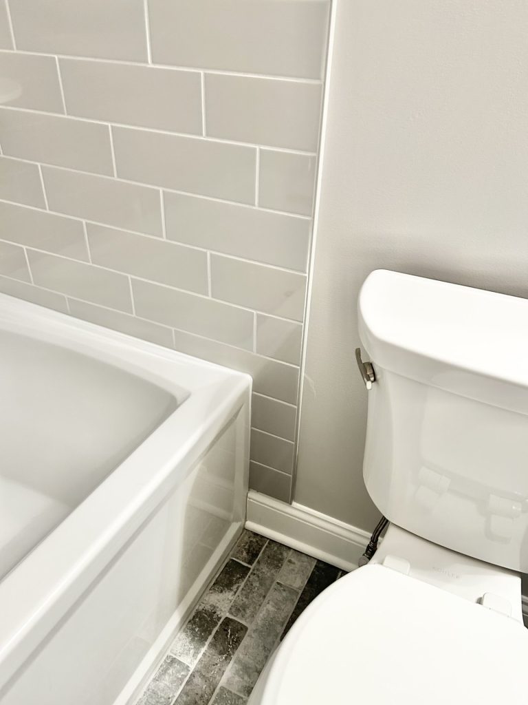 The Maple with Loft Bathroom Detail with White Tub, Gray Tile Accent, White Toilet & Tile Flooring