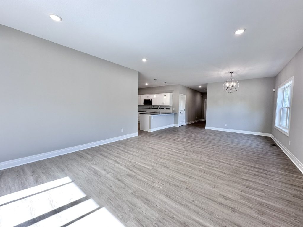 Large-Living-Dining-Area-with-Recessed-Lighting-Window-and-Modern-Light-Fixture-with-Kitchen-Tucked-in-Corner