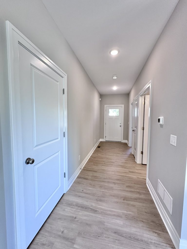 Pretty-Hallway-in-White-Neutrals-with-Recessed-Lighting-and-White-Entry-Door