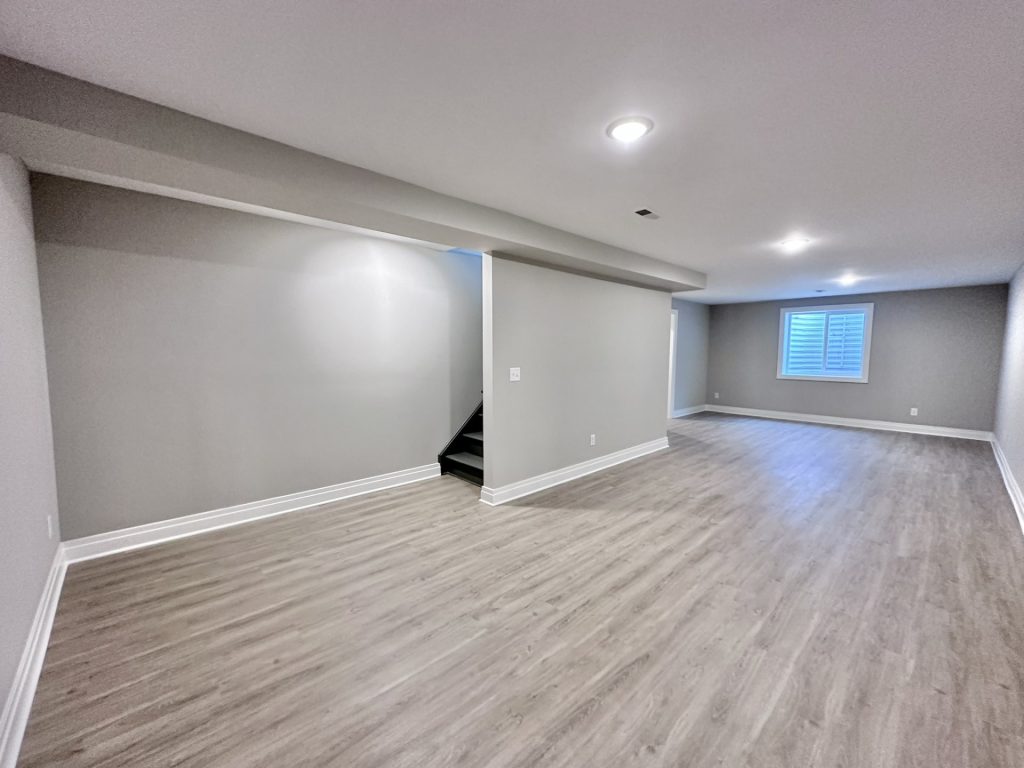 Finished-Lower-Level-in-Neutrals-with-Recessed-Lighting-Window