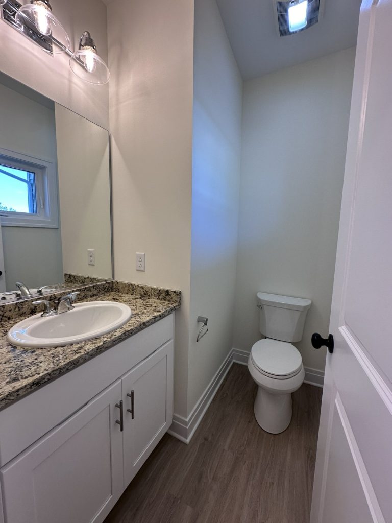 Madison-Half-Bathroom-with-Granite-Vanity-Top-White-Cabinetry-and-Wood-Look-Flooring