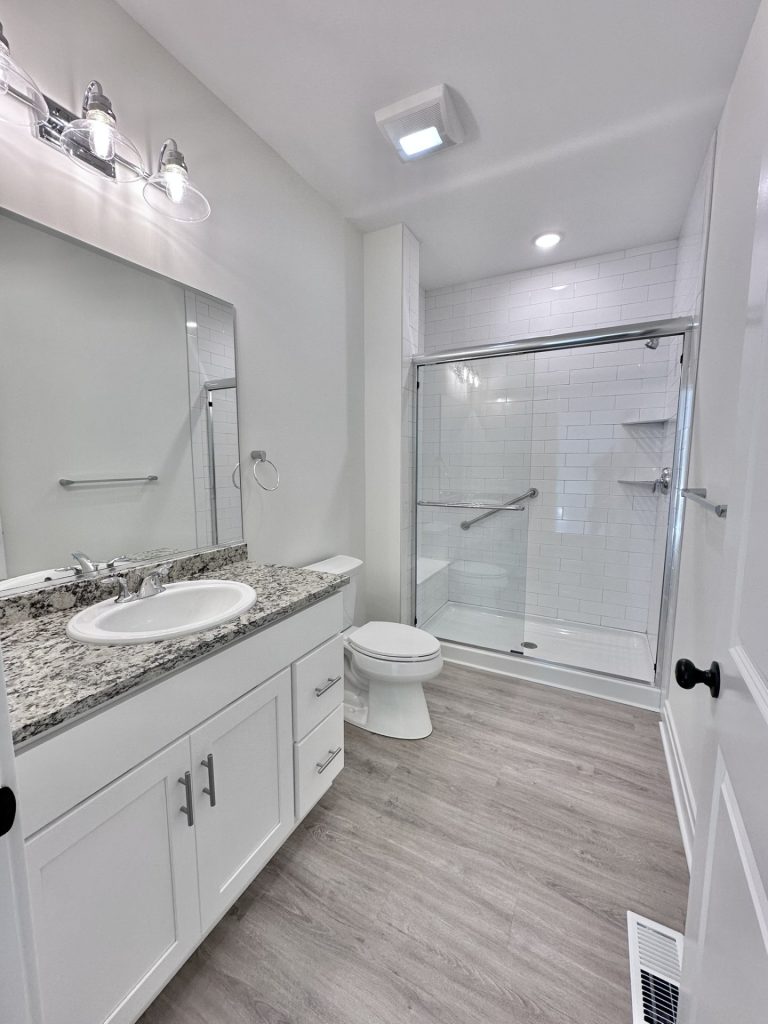 Madison-Primary-Bathroom-with-Granite-Vanity-Top-Glass-Enclosed-Shower-and-Wood-Look-Flooring