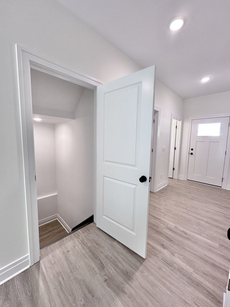 Madison-Entry-Hall-with-Wood-Look-Flooring-White-Front-Door-and-Stairwell-Access