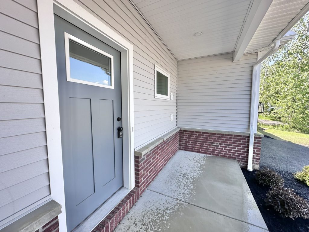 Madison-Covered-Front-Porch-with-Gray-Entry-Door-Light-Gray-Siding-and-Brick-Water-Table