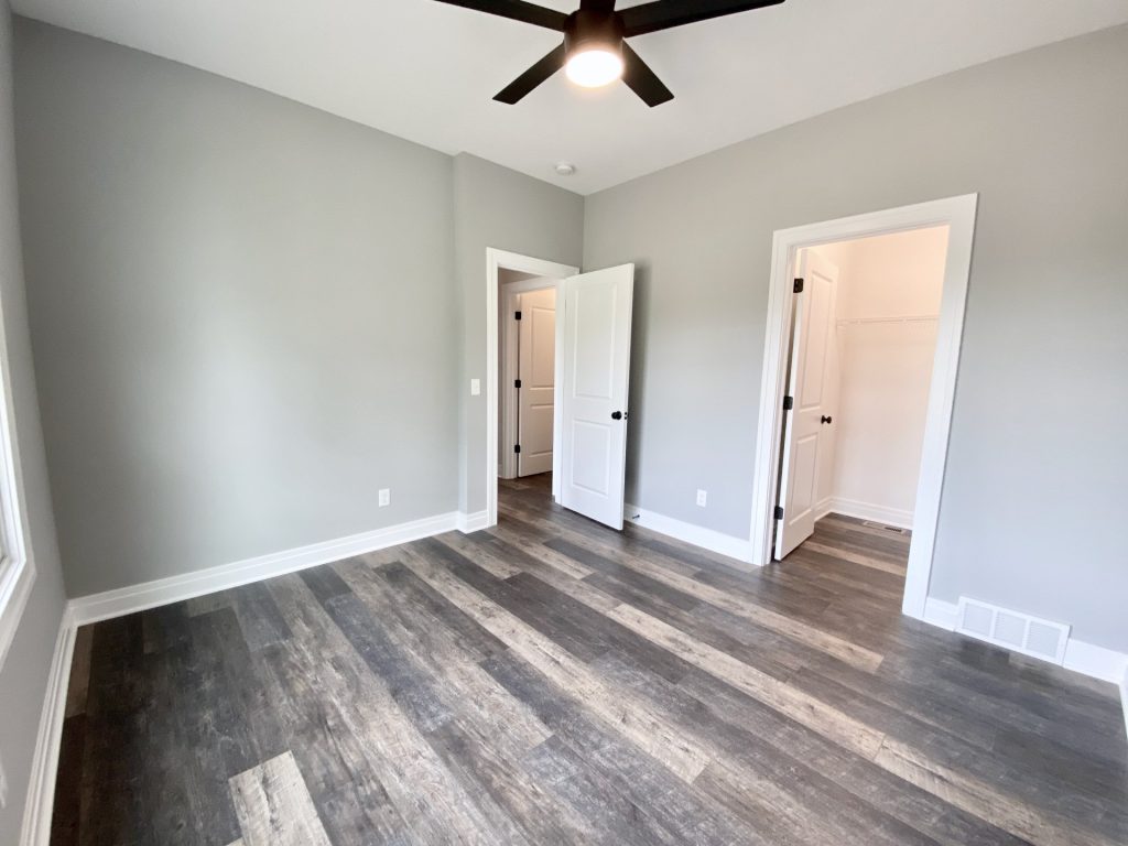 The Golden Bedroom with Walk-In Closet, Open Doorway, Gray Walls & Dark Ceiling Fan