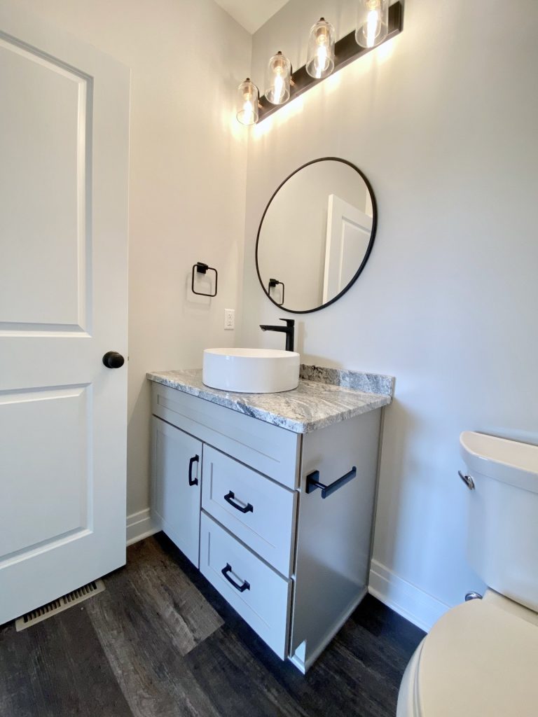 The Golden Gray Vanity with Vessel Sink, Round Mirror, Black Faucet & Wood-Look Flooring