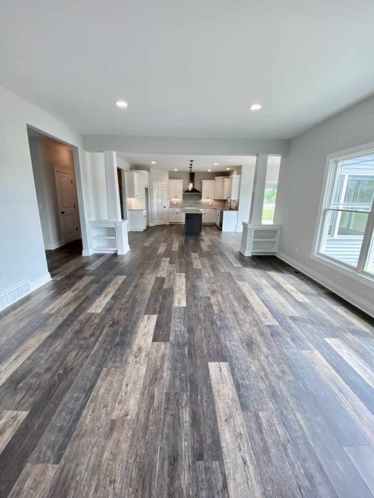The Golden Great Room with Kitchen View, Columns, Open Layout & Wood-Look Flooring