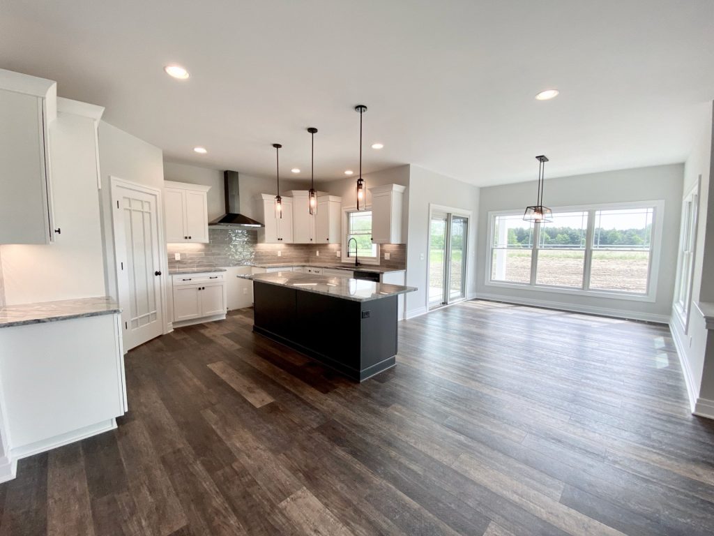 The Golden Open Kitchen and Dinette with Dark Island, Large Windows, Pendant Lights & Wood-Look Flooring