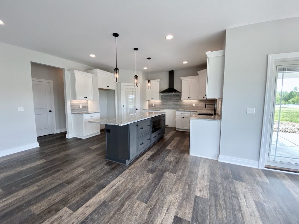 The Golden Kitchen with Dark Island, White Cabinetry, Sliding Glass Door & Pendant Lights