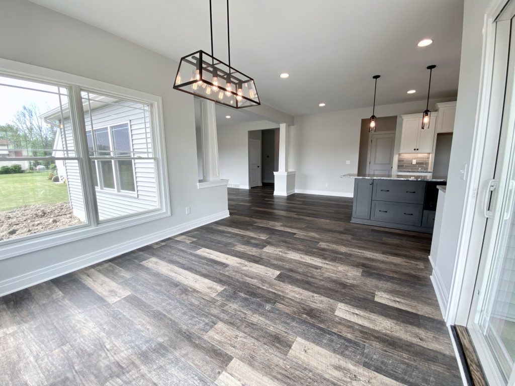 The Golden Dinette with Large Window, Linear Chandelier, Kitchen Island View & Wood-Look Flooring