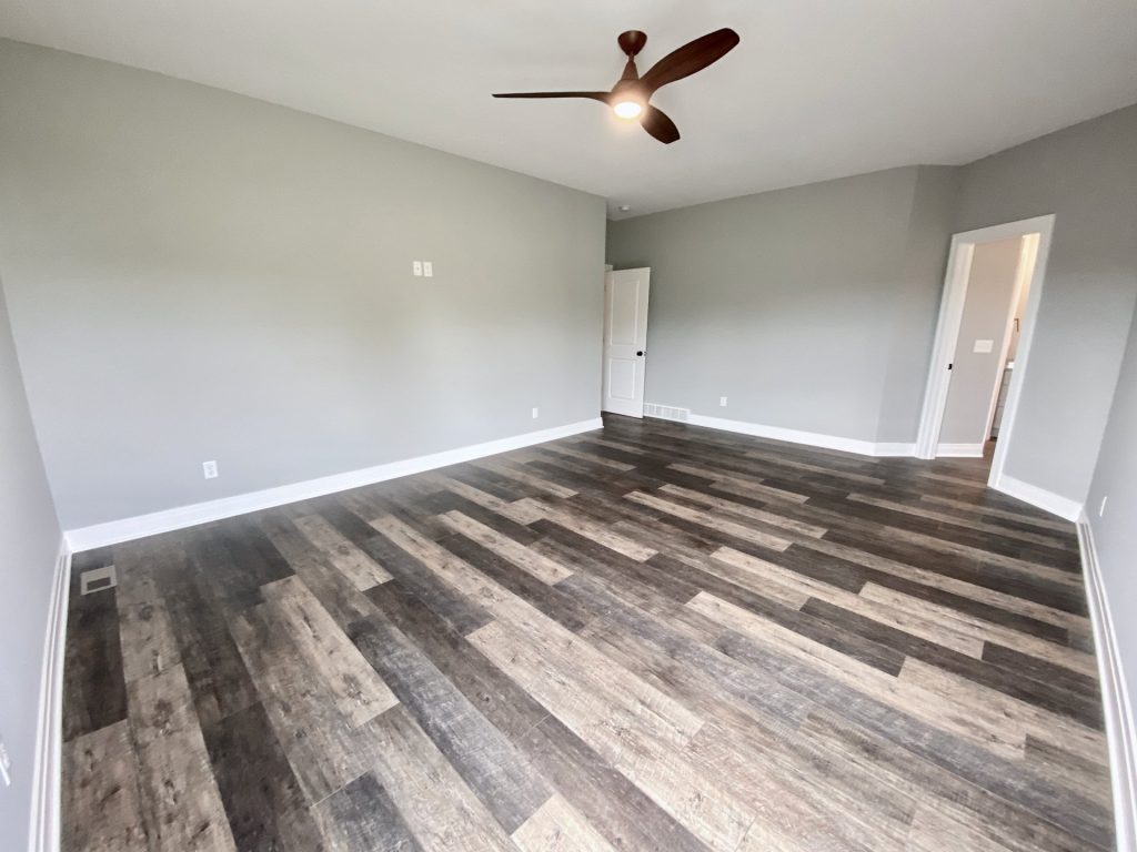 The Golden Primary Bedroom with Bathroom Entry, Gray Walls, Ceiling Fan & Wood-Look Flooring