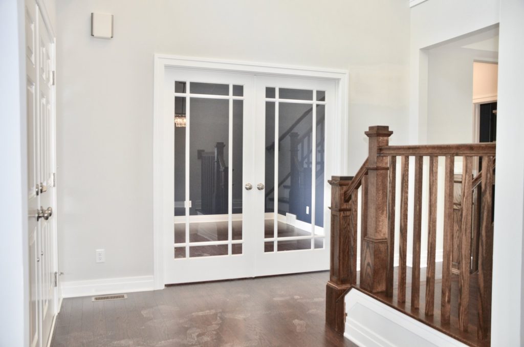 Arbordale-Foyer-with-Glass-French-Doors-Dark-Wood-Flooring-and-Stair-Rail-Detail
