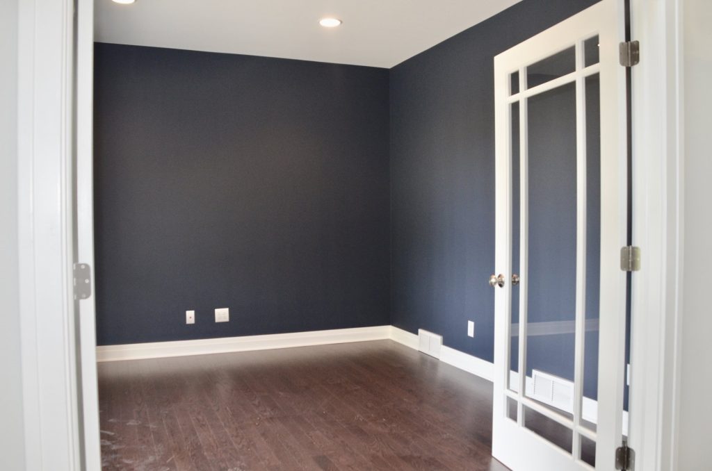 Arbordale-Front-Den-with-Dark-Blue-Accent-Walls-Dark-Wood-Flooring-and-Glass-French-Doors